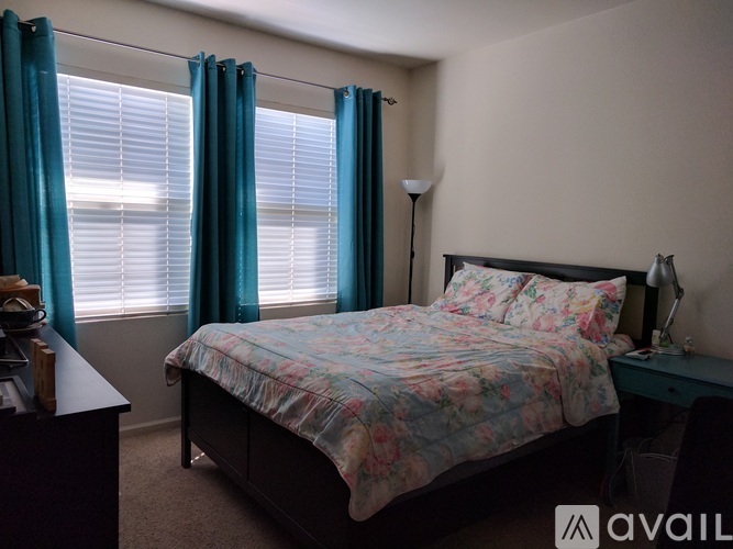 A bedroom with a bed, nightstand, and window with blue curtains.