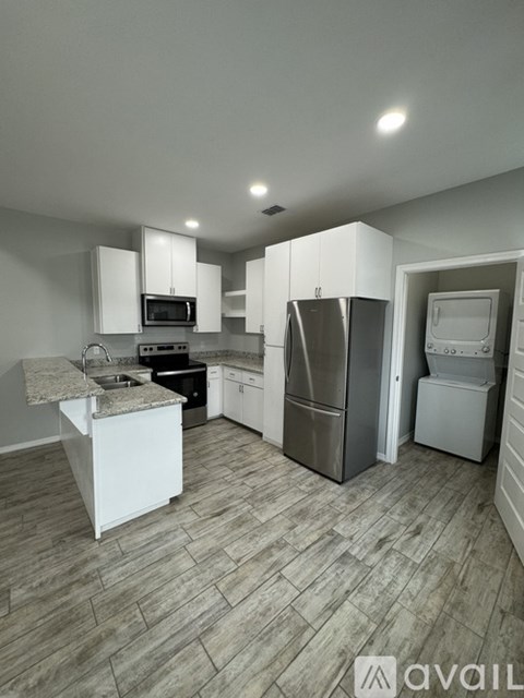 A kitchen with a refrigerator, microwave, oven, and sink.