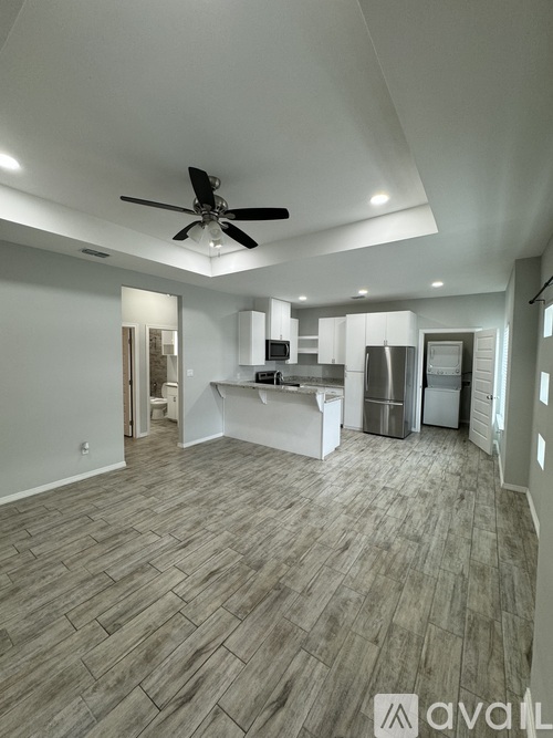 A spacious kitchen with a fan on the ceiling and a wooden floor.