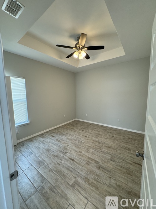 A room with a ceiling fan and light fixture, and a door with a handle.