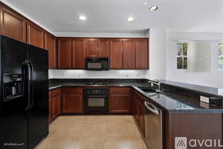 A kitchen with black appliances and brown cabinets.