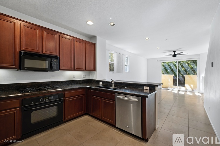 A kitchen with brown cabinets and black appliances.