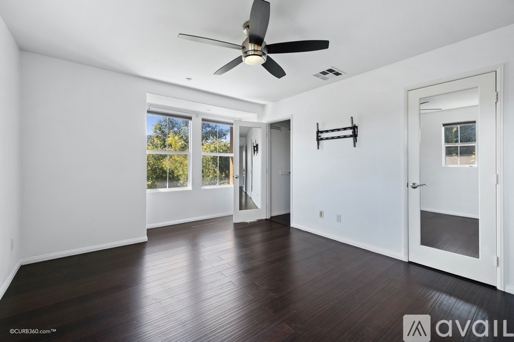 A spacious room with a ceiling fan and wooden flooring.