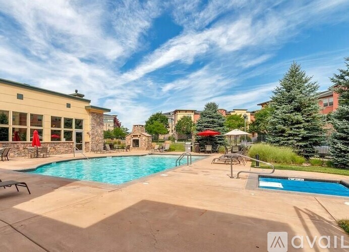 A pool area with a stone building and a red umbrella.
