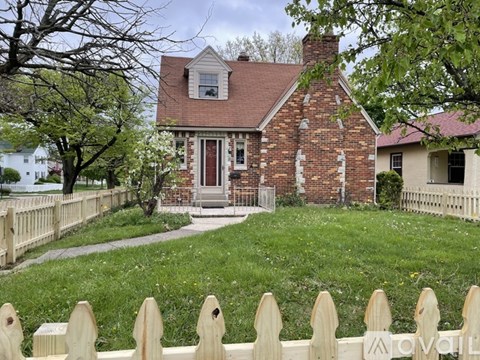 A house with a red brick exterior and a white picket fence.