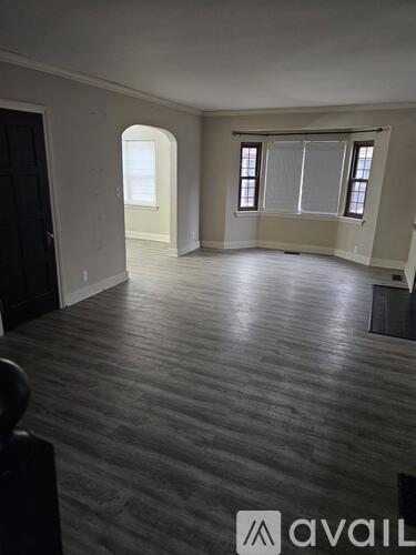 A room with wooden flooring and a window with blinds.