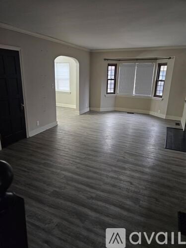 A room with wooden flooring and a window with blinds.