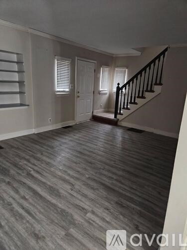 A room with wooden flooring and a staircase.