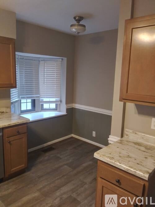 A kitchen with wooden cabinets and a marble countertop.