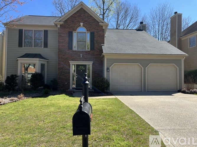 A house with a brick chimney and a black mailbox in front.