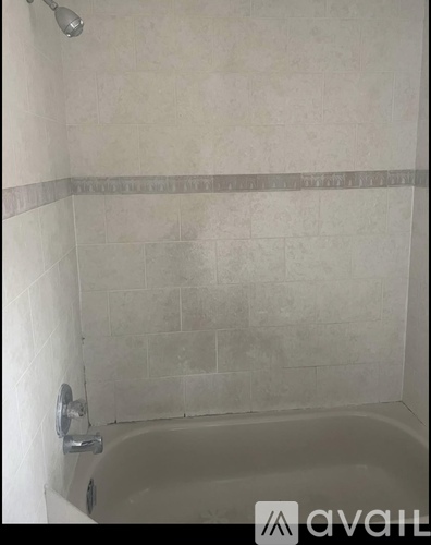 A bathroom with a white tub and tiled walls.