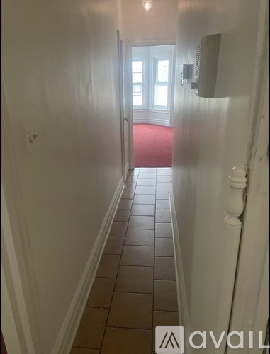 A hallway with a red carpet and tiled floor.