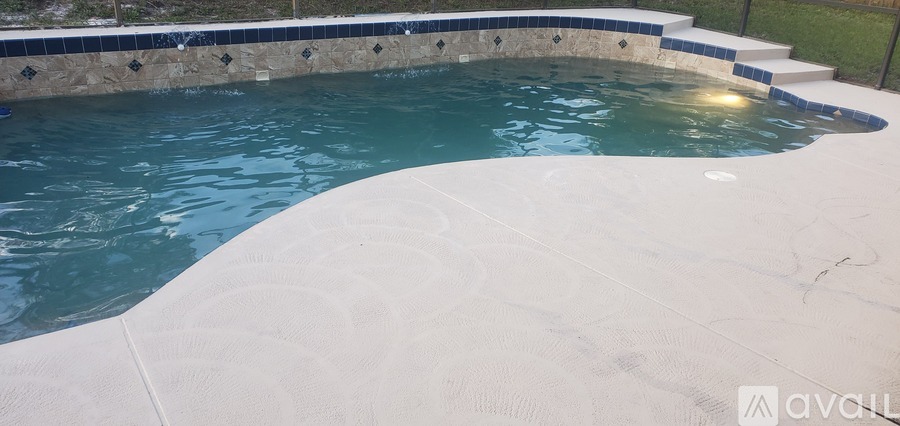 A pool with a blue tiled border and steps leading up to it.
