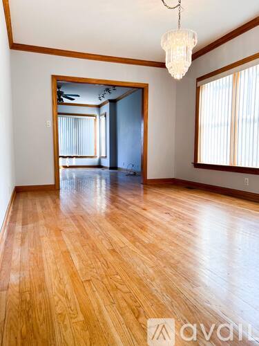 A room with wooden floors and a chandelier hanging from the ceiling.