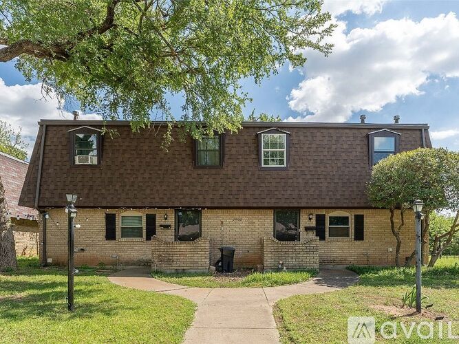 A house with a brown roof and a tree in front.