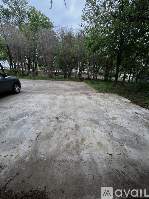 A car is parked on a dirt road with trees in the background.