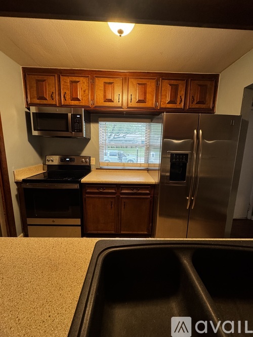 A kitchen with wooden cabinets and a stainless steel refrigerator.
