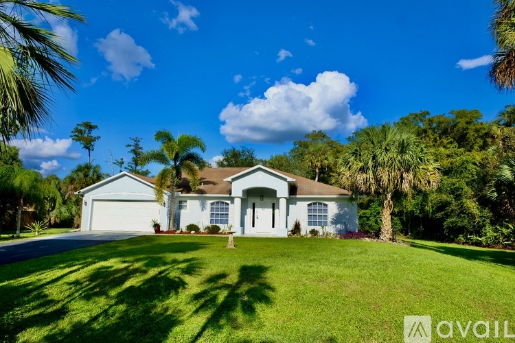 A house with a white front yard and a blue sky in the background.