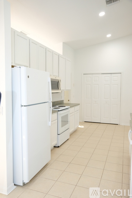 A white kitchen with a refrigerator, oven, and microwave.