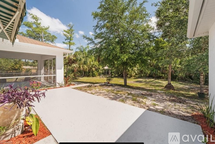 A white house with a green roof and a white fence with a white wall and a white walkway.