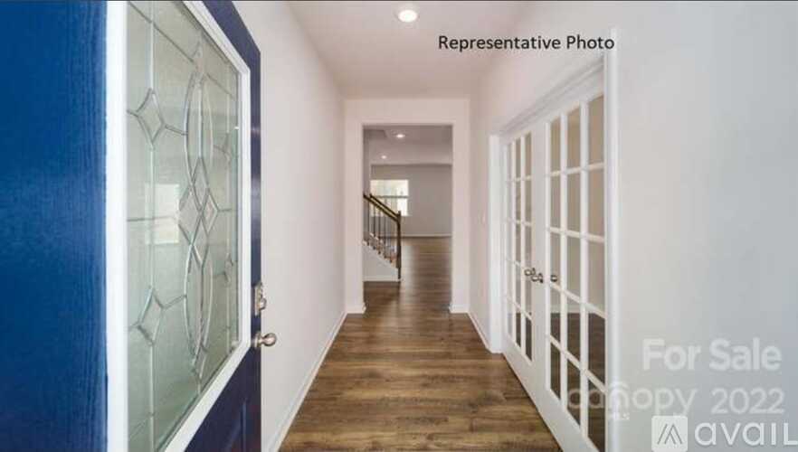 A hallway with a blue door and a staircase in the background.