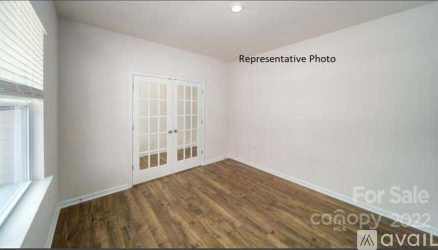 A room with a wooden floor and a white door is for sale.
