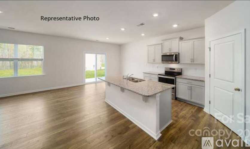 A kitchen with white cabinets and a wooden floor.