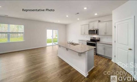 A kitchen with white cabinets and a wooden floor.