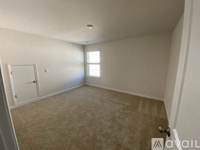 A room with a carpeted floor and a door on the left side.
