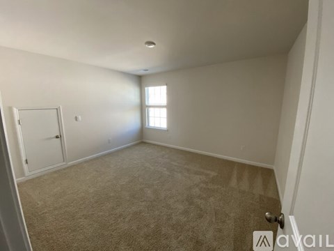 A room with a carpeted floor and a door on the left side.