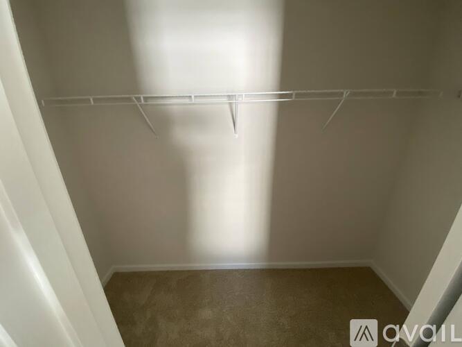Empty room with a white wall and a brown floor.