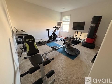 A home gym with a variety of equipment including a stationary bike, a rowing machine, and a bench press.