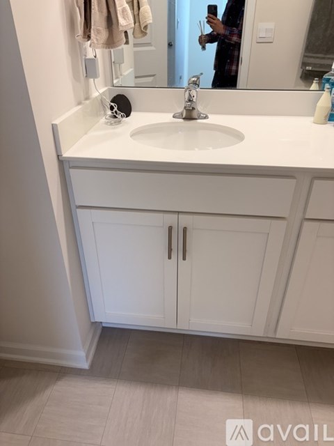 A bathroom with a white sink and cabinets.