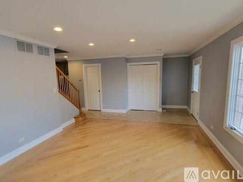 A spacious room with wooden flooring and a staircase.