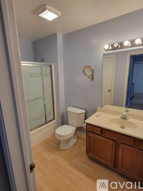 A bathroom with a toilet, sink, mirror, and shower.
