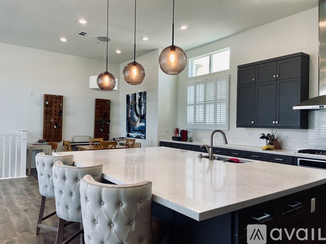 A modern kitchen with a large island and pendant lights.