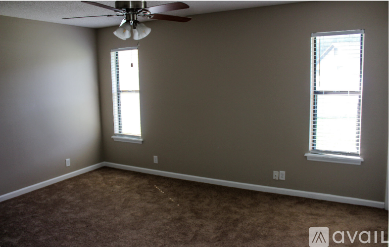 A room with a ceiling fan and two windows.