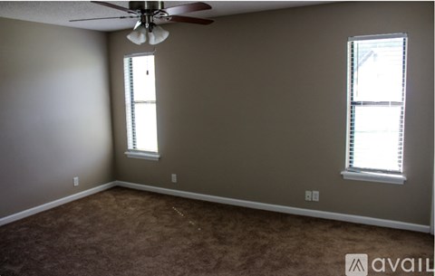 A room with a ceiling fan and two windows.