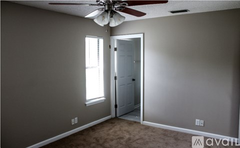 A room with a ceiling fan and a door leading to another room.