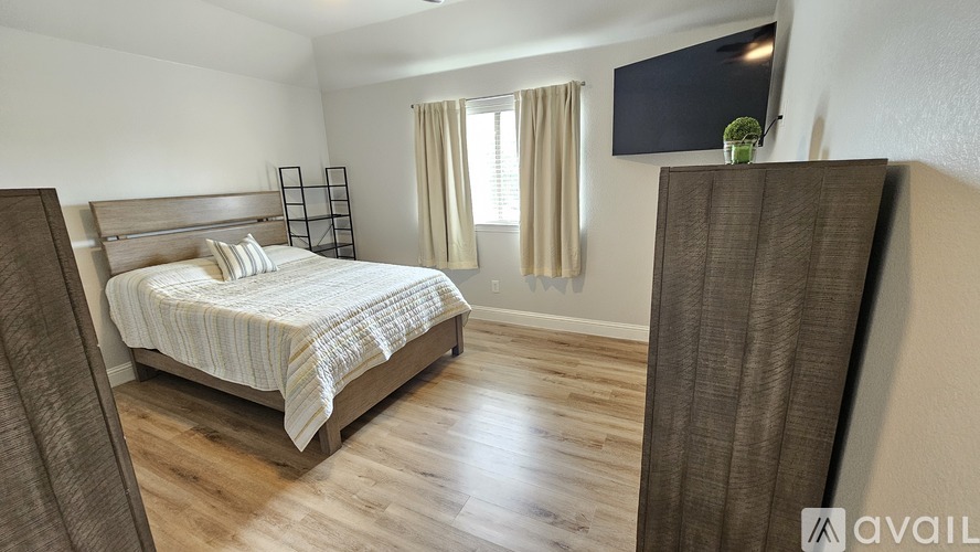 A bedroom with a large bed and a flat screen TV mounted on the wall.