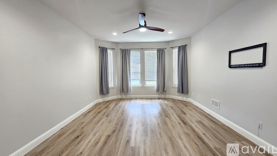 A spacious room with wooden flooring and a ceiling fan.