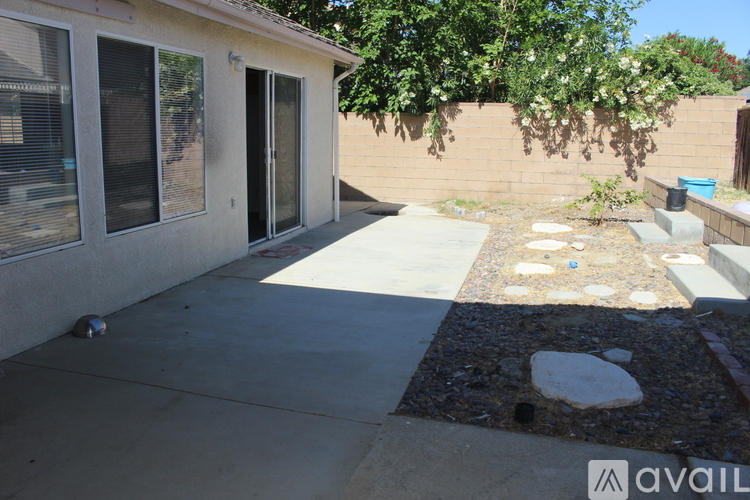 A backyard with a concrete patio and a small garden area.