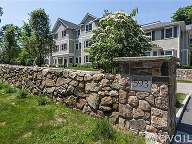 A stone wall with a sign that reads 593 in front of a building.