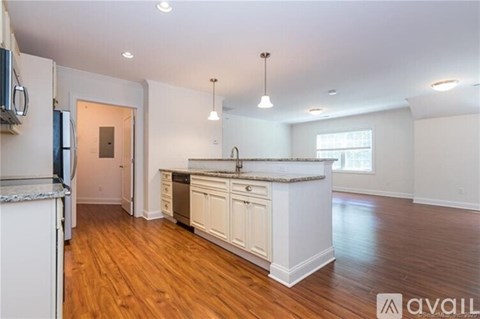 A kitchen with white cabinets and a wooden floor.
