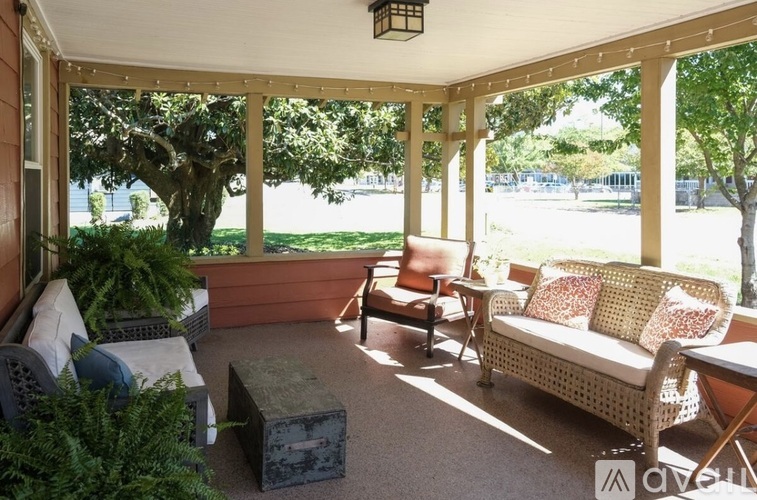 A sunny day on a covered patio with a couch, chair, and table.