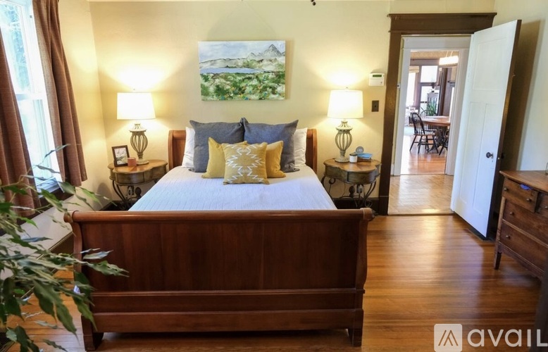 A bedroom with a bed, two lamps, and a painting on the wall.