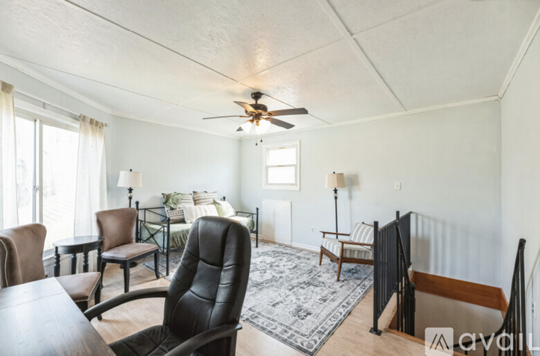 A living room with a black leather chair and a ceiling fan.