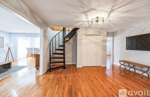 A spacious room with wooden floors and a staircase.