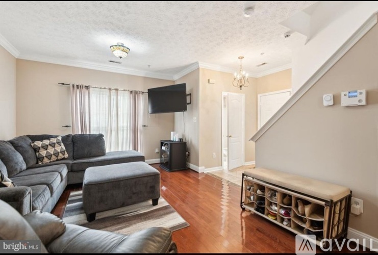 A living room with a grey couch and a television on the wall.
