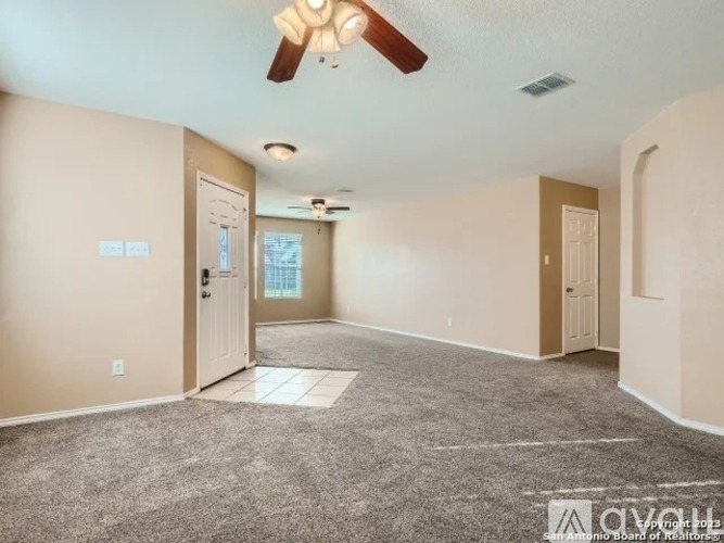 A spacious room with a ceiling fan and carpeted floor.